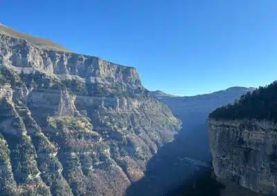 Cañón del Valle de Ordesa con paredes estratificadas y bosques bajo cielo despejado